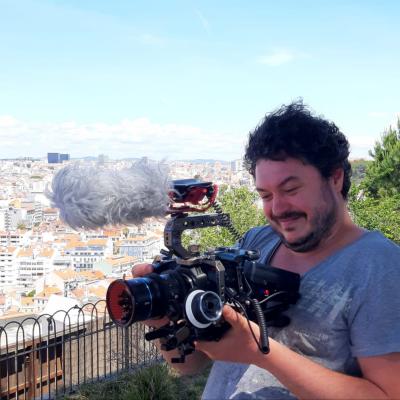 Auf diesem Foto ist ein Mann zu sehen, der eine Kamera hält. Im Hintergrund ist Lissabon. 